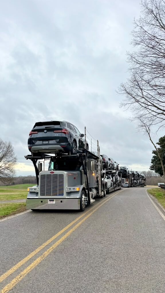 Line of loaded car carriers on a country road, BMW X5 on the headrack