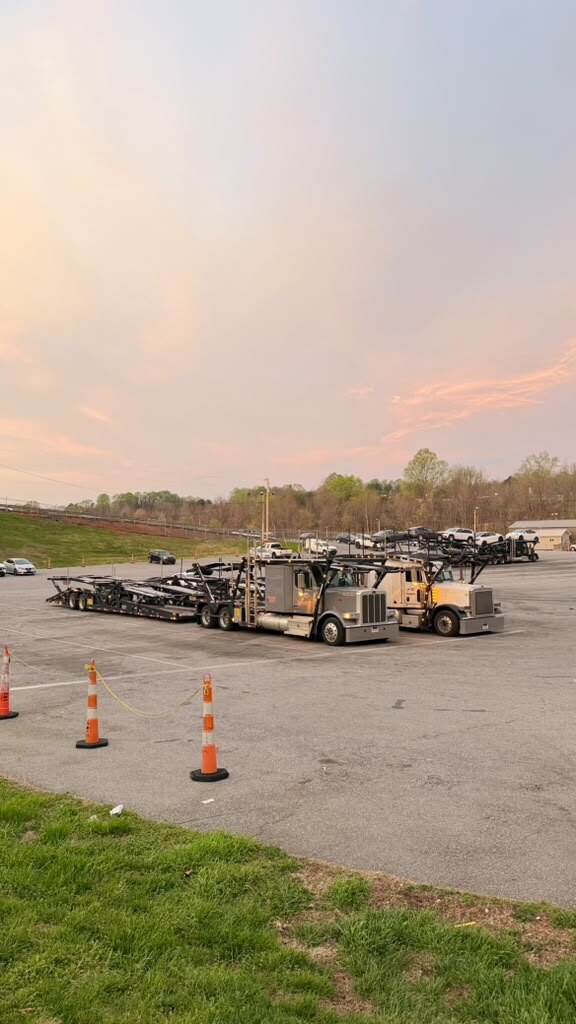 Two empty car carriers parked at sunset