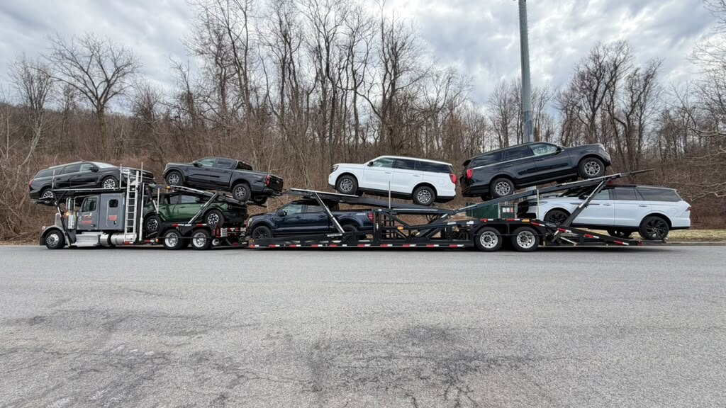 Loaded car carrier parked by bare winter trees