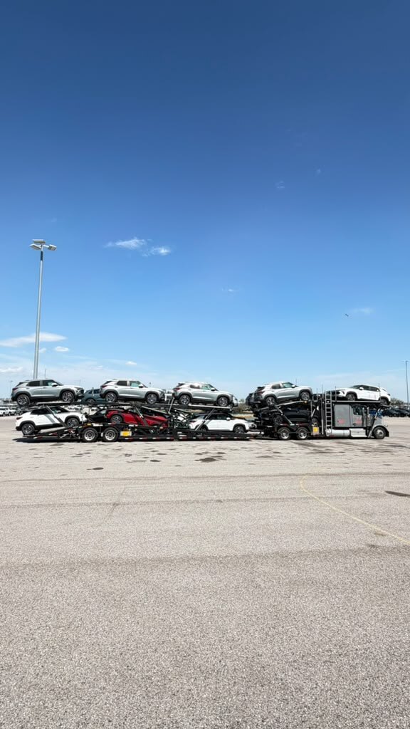 Loaded car carrier on an open lot under a clear blue sky